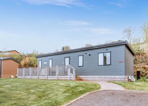 A single-story mobile home with a front porch, a small attached garage, and a paved driveway.
