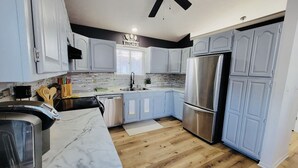 Una cocina moderna con armarios azul claro, un refrigerador de acero inoxidable y piso de madera.