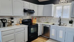 Una cocina moderna con armarios blancos, una estufa negra y un lavavajillas.