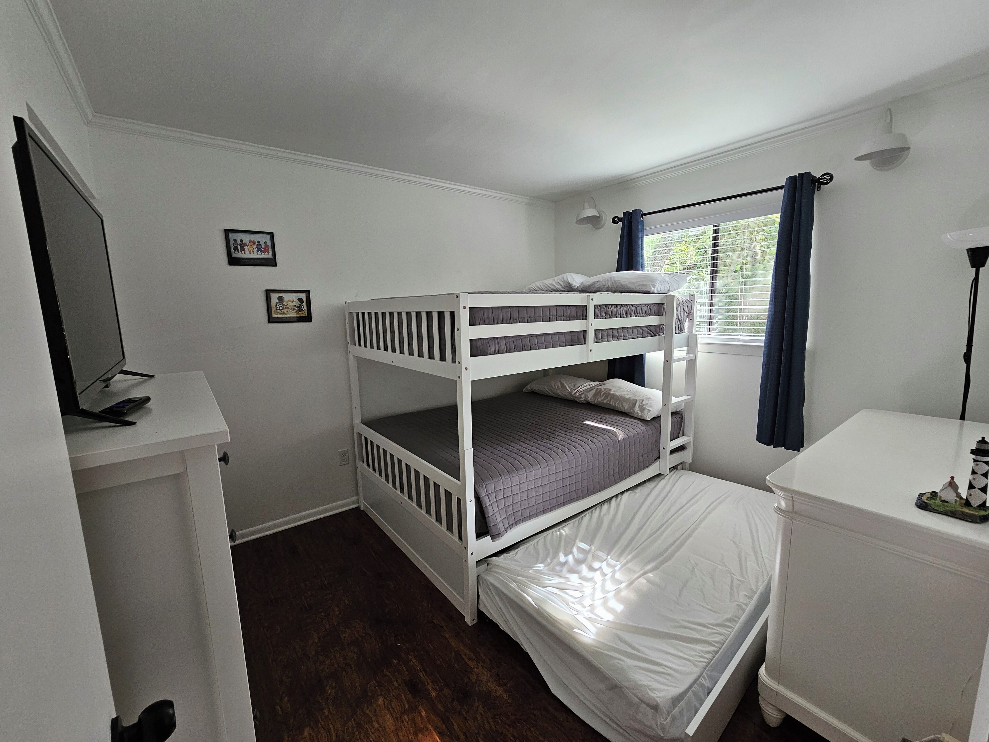 Une chambre avec un lit superposé, un bureau et un petit placard.