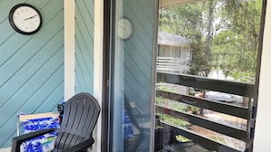 Un balcon avec deux chaises noires, une petite table et une horloge au mur.