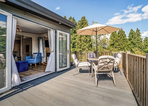A deck with outdoor furniture, a table, and a large umbrella.