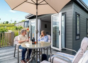 A couple seated at an outdoor table with a large umbrella, a bottle of champagne, and a glass of wine. - 2 bedroom accommodation in Bridgnorth (Bridgnorth)