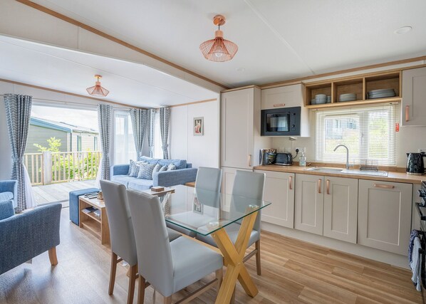 Eine moderne Küche mit Essbereich, einer Couch und einem Balkon mit Vorhängen.