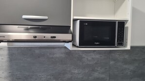 A compact kitchen with a built-in stove and microwave. - Fully furnished and air-conditioned apartment (Les Abymes)