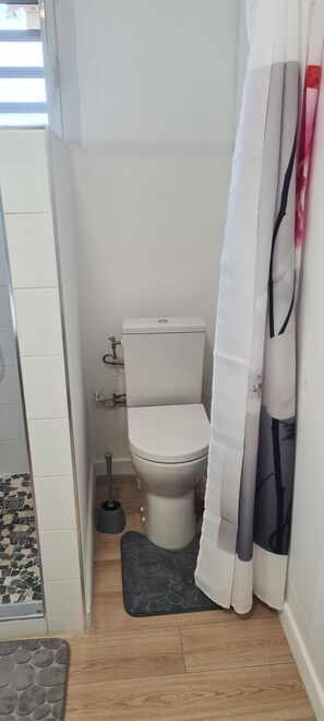 Bathroom features a toilet, shower curtain, and tiled floor.