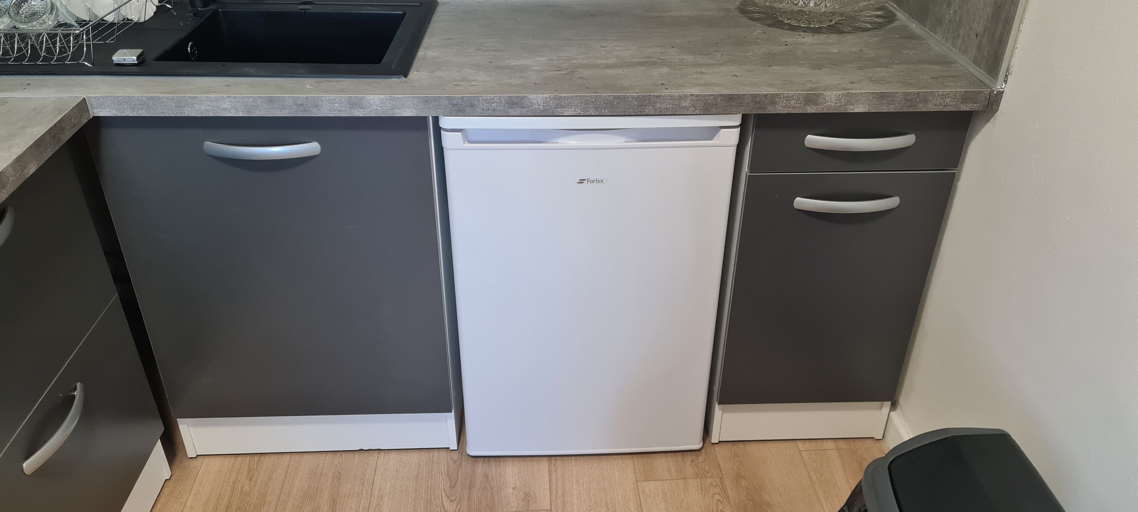 A compact kitchen with a dishwasher, two cabinets, and a countertop.