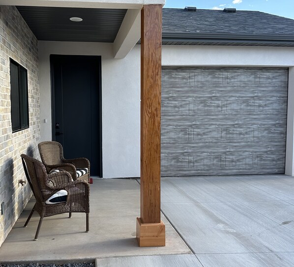 A modern house with a concrete porch, a wicker chair, and a garage door. - PET FRIENDLY Harry Potter Themed TWO King Size Beds Cozy Mountain View’s! (Cedar City)