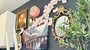 A wall with framed artwork, a decorative mirror, and a candle holder.