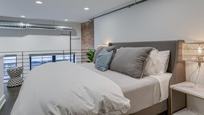 Un dormitorio moderno con una cama, mesita de noche y vistas a la ciudad.