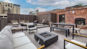 Un patio al aire libre con un brasero, asientos y un muro de ladrillo.