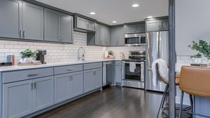 Una cocina moderna con armarios grises, un refrigerador de acero inoxidable y un horno empotrado.