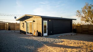 Un edificio moderno a un piano con un'ampia porta garage, un portico coperto e un vialetto sterrato.