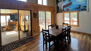 A spacious dining area with a wooden table and chairs, large windows, and a painting of a lake scene. - Minnesota lakefront home/cabin near Tower and Ely, close to Bear Head State Park (Ely)