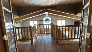 An interior view of a wooden cabin with a sloped ceiling, a central skylight, and a wooden staircase leading to an upper level. - Minnesota lakefront home/cabin near Tower and Ely, close to Bear Head State Park (Ely)