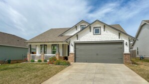 A single-story house with a front porch, a garage, and a well-maintained lawn. - Minutes from Tulsa!  Come relax with the family in this pet friendly home  (Owasso)
