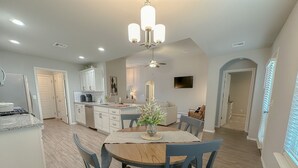 A modern kitchen with a dining area, featuring a central island, pendant lighting, and a ceiling fan. - Minutes from Tulsa!  Come relax with the family in this pet friendly home  (Owasso)