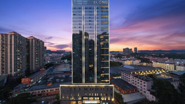 A high-rise building with the name "BELONG" at the top, surrounded by other buildings and a parking lot. - Elong Hotel Shenzhen South China City (Shenzhen)