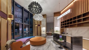 A modern hotel lobby with a reception desk, seating area, and large windows overlooking a cityscape. - Elong Hotel Shenzhen South China City (Shenzhen)