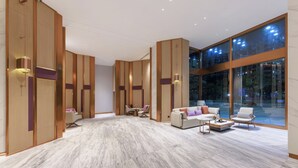 A spacious hotel lobby with a modern design, featuring a seating area with sofas and chairs, a coffee table, and a large window offering a view of the cityscape. - Elong Hotel Shenzhen South China City (Shenzhen)