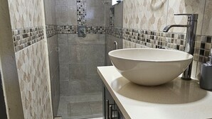 Une salle de bain avec un grand lavabo, une douche et des murs carrelés.