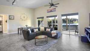 A spacious living room with a sectional sofa, a coffee table, and a large window offering a view of the outdoors.
