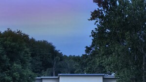 A modern house with a balcony, reflecting in a calm lake at dusk.