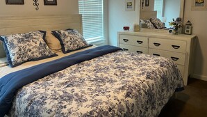 Une chambre à coucher avec un lit, une commode et un grand miroir.