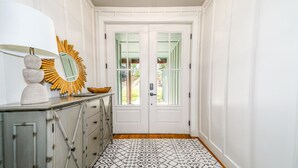 A hallway with a white door, a decorative mirror, and a patterned rug. - The Gallery of Monkey Island [ WITH 28x14 BOAT SLIP] (Monkey Island)