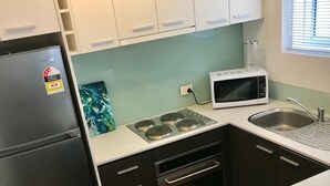 Una cocina compacta equipada con refrigerador, microondas, estufa, horno y pileta.