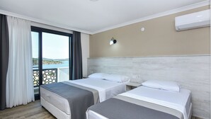 A hotel room with two beds, a balcony with a view, an air conditioning unit, and a wall-mounted light fixture. - Beyaz Konak Otel (Ayvalik)