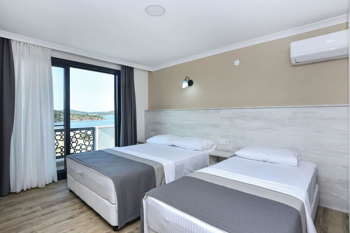 Een hotelkamer met twee bedden, een balkon met uitzicht, een airconditioning en een wandlamp.