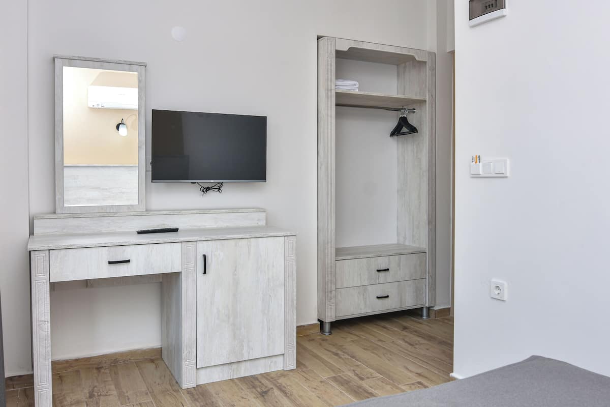 Een moderne slaapkamer met een houten kaptafel, een flatscreen-televisie en een kledingkast.