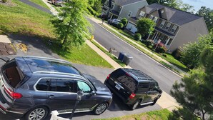 Une rue résidentielle avec deux voitures garées et des maisons de chaque côté.