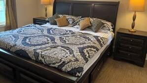 Un lit bien fait, avec une literie à motifs, deux tables de chevet avec des lampes et une tête de lit en bois foncé.