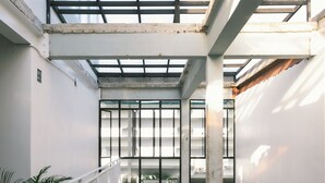 Un intérieur à plusieurs niveaux, doté d’un plafond en verre, de piliers en béton et d’une rambarde en métal.