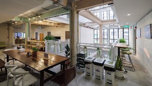 Un bureau à aire ouverte avec de hauts plafonds, de grandes fenêtres et un mobilier moderne.
