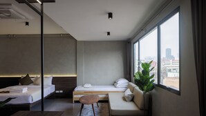 Une chambre d’hôtel moderne équipée d’un lit, d’un canapé, d’une petite table et d’une grande fenêtre donnant sur la ville.