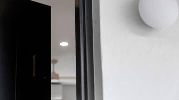 Ein modernes Interieur mit einer schwarzen Tür, die mit der Nummer 1 gekennzeichnet ist, einer weißen Wand und einer kugelförmigen Leuchte.
