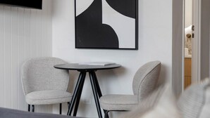 A modern room with two grey upholstered chairs, a small round table, and a black and white abstract painting on the wall.