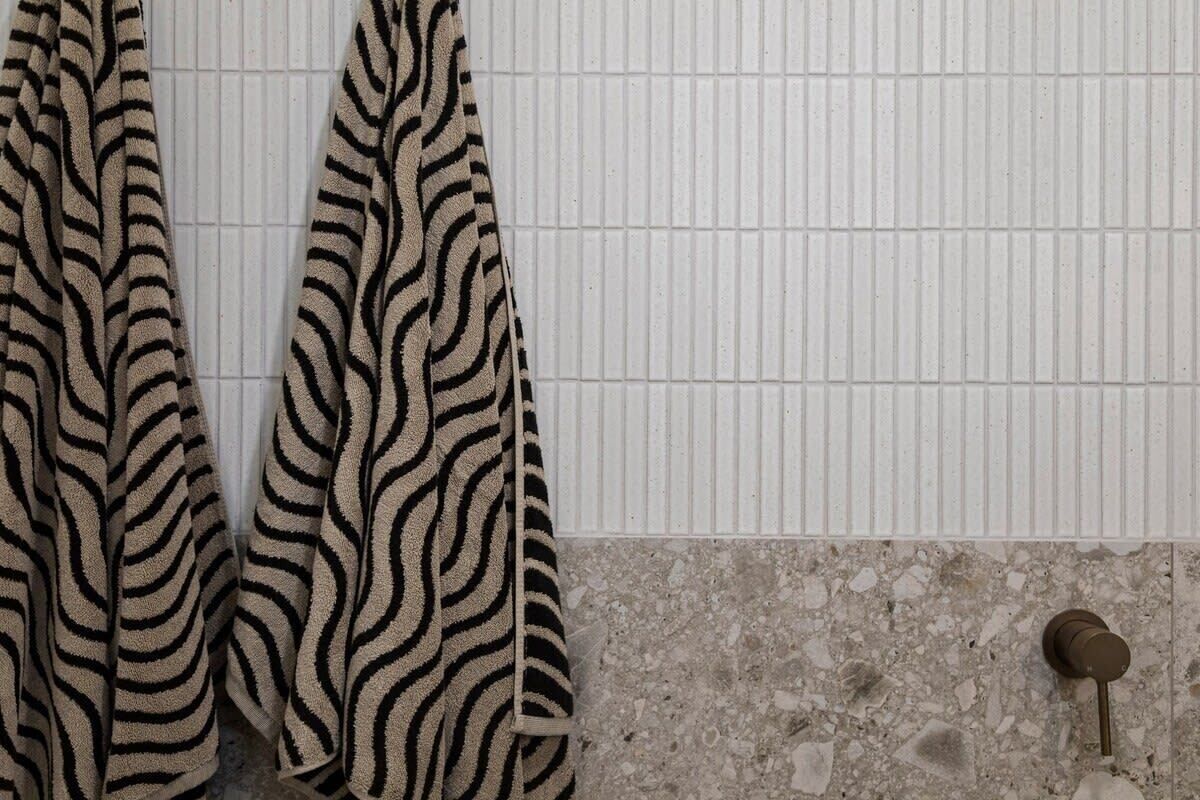 Ett badrum med en handduk i zebrastripe som hänger på en handdukshängare, en kaklad vägg och en dörr med ett nyckelhål.