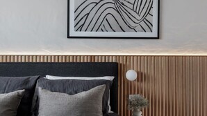 A modern bedroom with a dark headboard, striped pillows, a framed abstract artwork, and a wooden panel wall. - The Lodge - Room 2 - Luxury Central private Rooms, Free wifi (Mount Gambier)