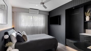A modern bedroom with a bed, bedside table, and a TV mounted on the wall.
