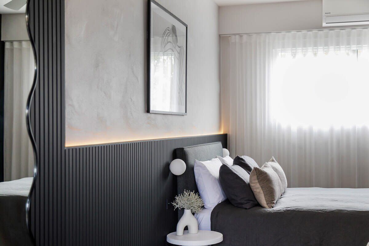 A modern bedroom with a bed, bedside table, and a framed picture on the wall.