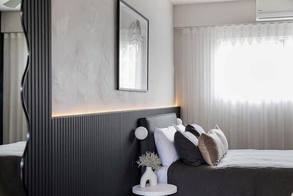 Ein modernes Schlafzimmer mit Bett, Nachttisch und einem gerahmten Bild an der Wand.