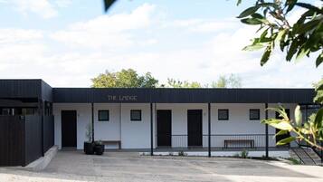 A modern building named "The Lodge" with a minimalist design, featuring a flat roof, a central entrance, and a small outdoor seating area.