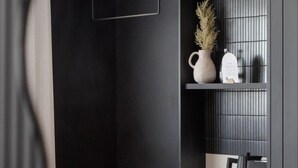 Un dormitorio moderno con armario empotrado, mesita de noche y una pequeña estantería con objetos decorativos.