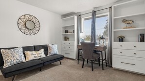 A modern living room with a black sofa, a dining table with two chairs, and white shelving units. - Cozy 3BR modern farmhouse in Rochester with stone fireplace, fenced yard, and easy I-5 access. (Rochester)