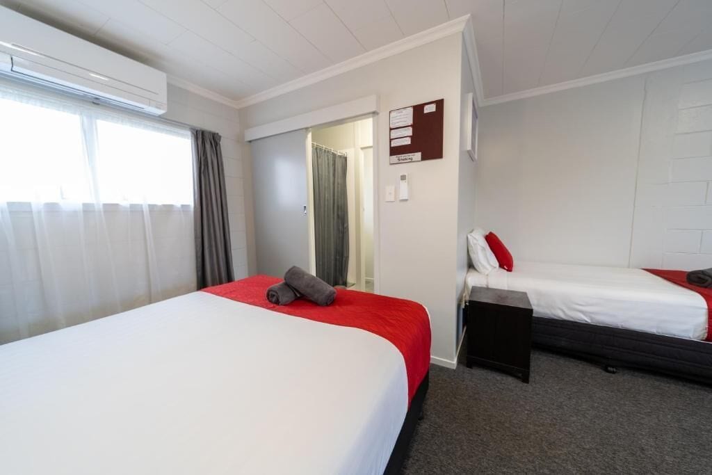 A hotel room with two beds, a desk, and a bulletin board.