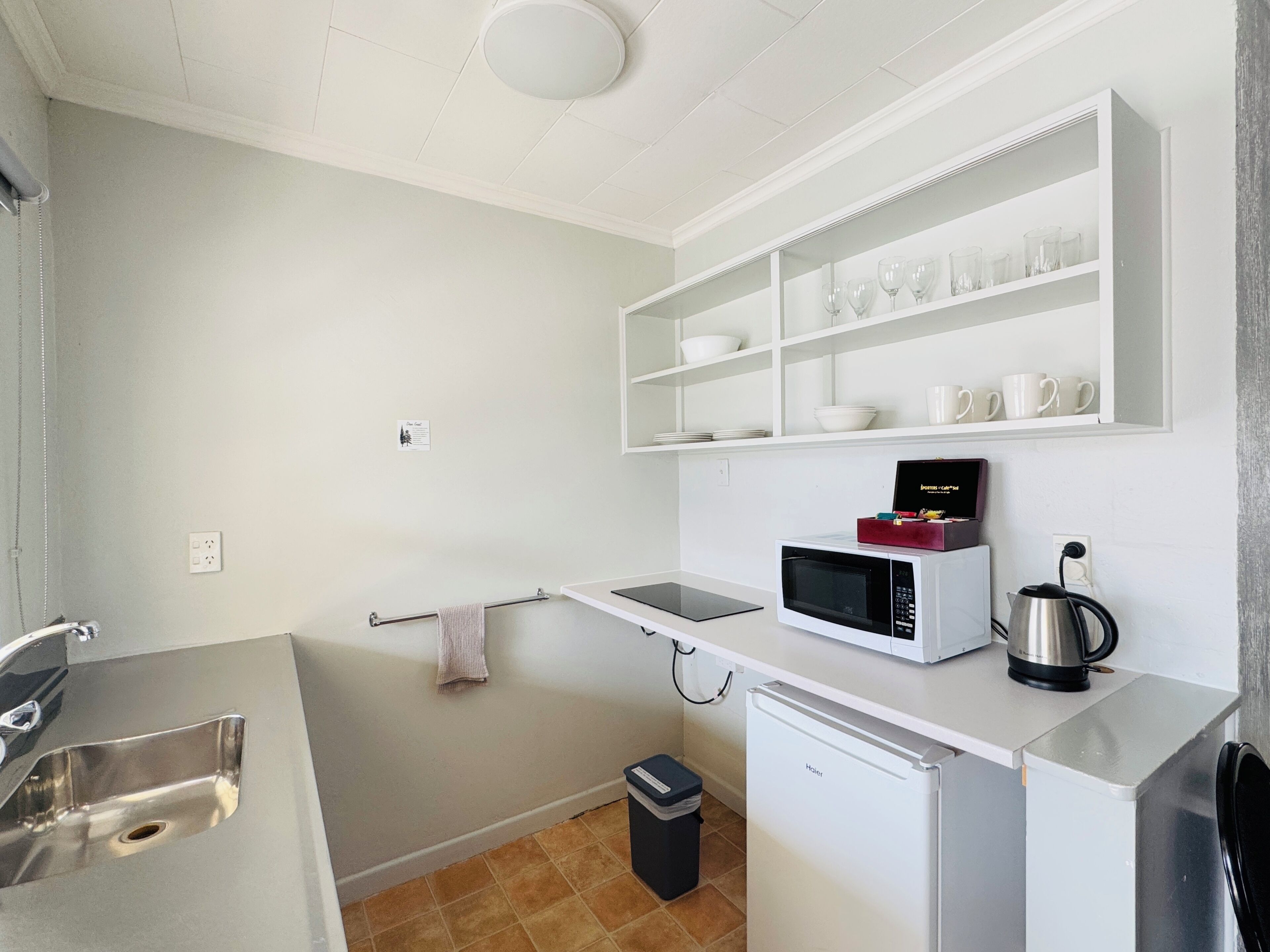 Una kitchenette compacta con microondas, hervidor y un refrigerador pequeño.